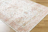Close-up of the Lotan Pink Medallion Washable Area Rug. Features a traditional medallion pattern in light gray, tan, and sterling gray. Corner
