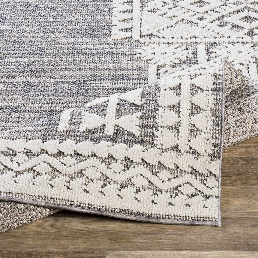 Close-up of the textured Luddenham Outdoor Rug. Farmhouse style rug in black, gray, and white with geometric pattern. Fold