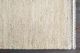 Close-up of the hand woven Lumatil Area Rug. Jute and wool rug in cream, light beige, and charcoal. Corner