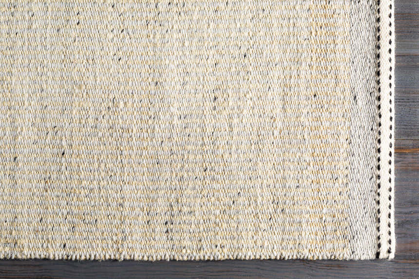 Close-up of the hand woven Lumatil Area Rug. Jute and wool rug in cream, light beige, and charcoal. Corner