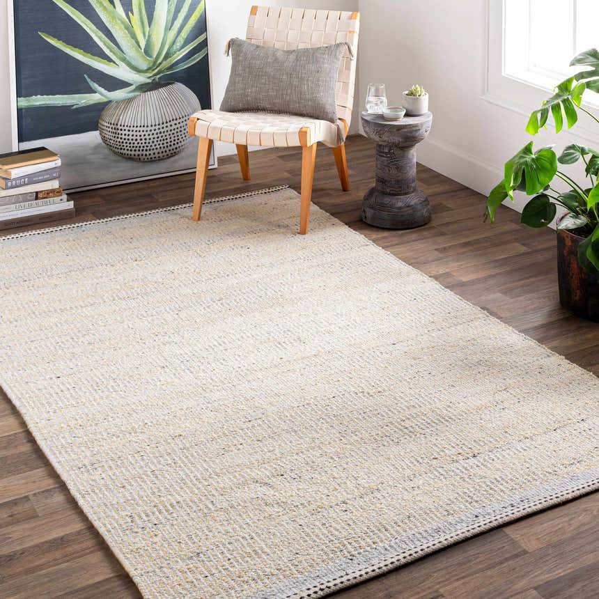 Living room scene with a cream and light beige Lumatil Area Rug, woven chair, art, and plants. Roomscene-Rectangle