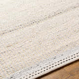 Close-up of the hand woven Lumatil Area Rug. Jute and wool rug in cream, light beige, and charcoal on wood floor. Texture