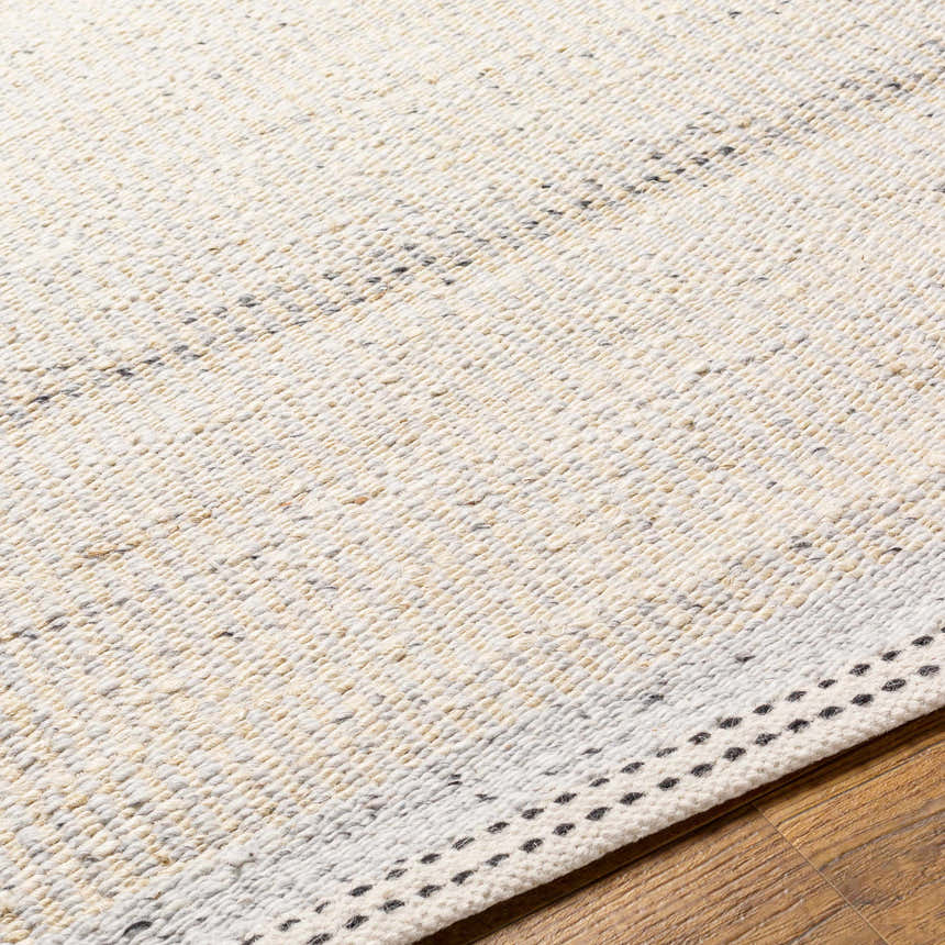Close-up of the hand woven Lumatil Area Rug. Jute and wool rug in cream, light beige, and charcoal on wood floor. Texture