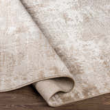 Close-up of the Lumbia Distressed Embossed Area Rug. Features a textured, abstract pattern in neutral beige and cream tones. Fold