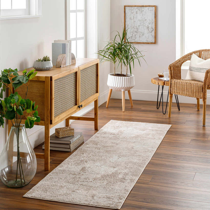 Living room scene with a Lumbia Distressed Embossed Area Rug, wood floors, console table, plants, and wicker chair. Roomscene-Runner