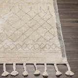 Close up of the Luncarty Area Rug. Cream rug with gray diamond pattern and braided tassels on dark wood floor. Front
