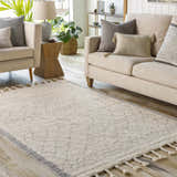 Living room scene with a cream sofa and the cream and gray Luncarty Area Rug with tassels on a wood floor. Roomscene-Rectangle
