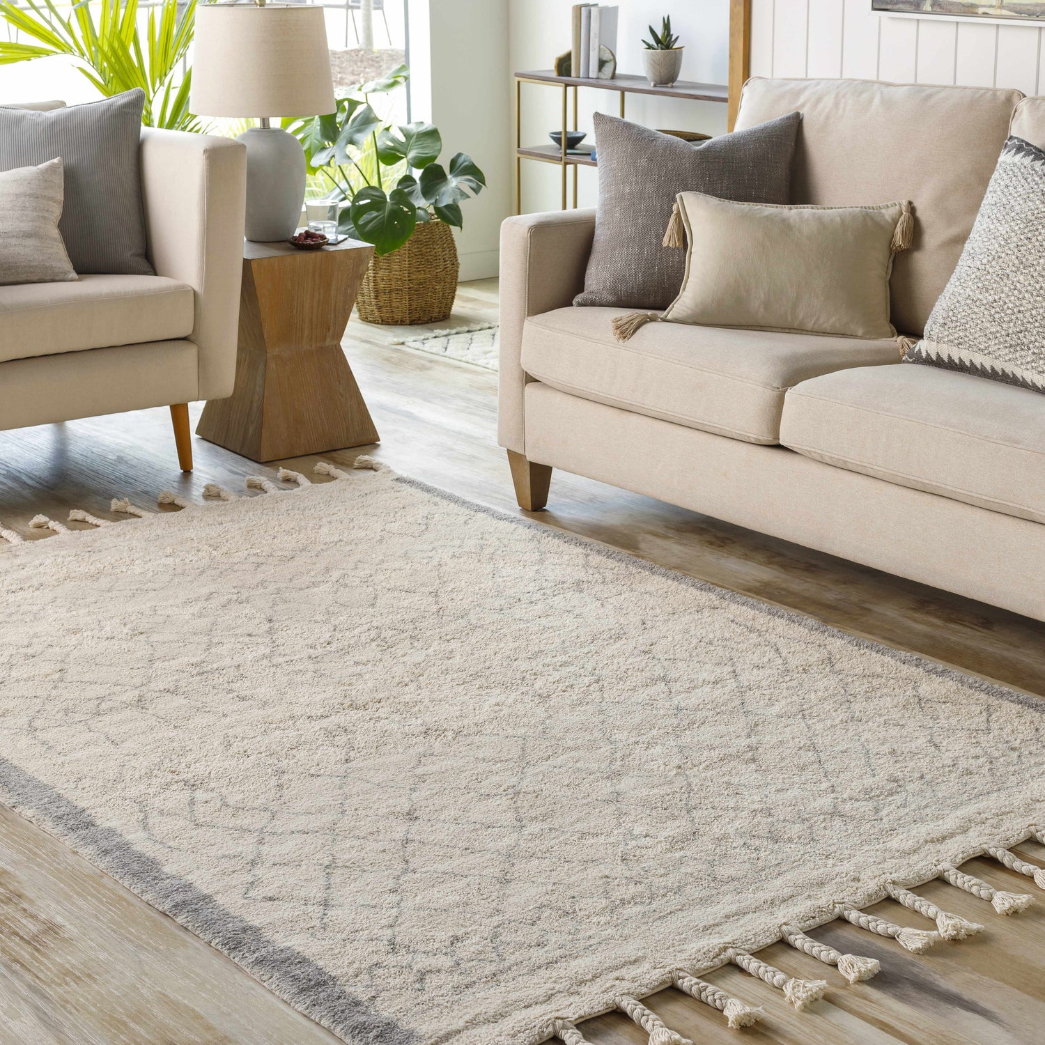 Living room scene with a cream sofa and the cream and gray Luncarty Area Rug with tassels on a wood floor. Roomscene-Rectangle