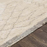 Close-up of the hand woven Luncarty Area Rug. Cream rug with a subtle gray geometric pattern on a dark wood floor. Pile