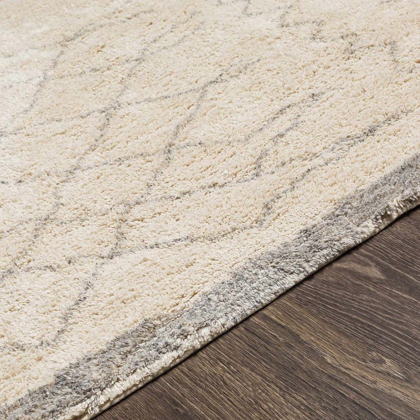 Close-up of the hand woven Luncarty Area Rug. Cream rug with a subtle gray geometric pattern on a dark wood floor. Pile