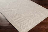 Close-up of Lusacan Area Carpet in charcoal, gray, and off-white with a geometric diamond pattern on dark wood flooring. Corner