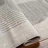 Close up of the Elvi Area Rug in natural gray, with a subtle geometric striped pattern and soft, textured pile. Fold