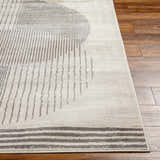 Close up of the Elvi Area Rug in natural gray with a geometric pattern on a wood floor. Front
