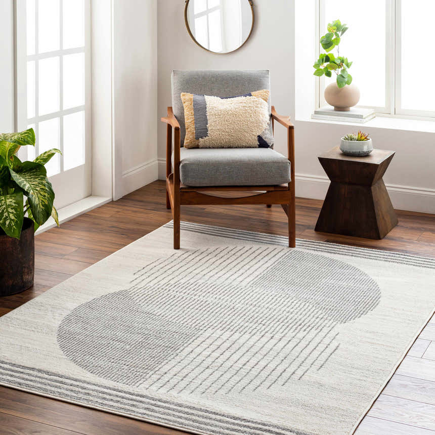 Living room scene with a gray chair and Elvi Area Rug in gray and white with a geometric pattern. Roomscene-Rectangle