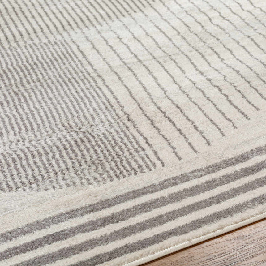 Close up of Elvi Area Rug showing its gray geometric pattern and soft texture on wood floor. Texture