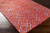 Close-up of the Loyalhanna Area Rug featuring a geometric pattern in gray, medium brown, and rust on dark wood flooring. Corner