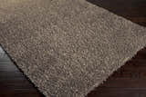 Close-up of the charcoal Morris Area Rug showing its soft, hand-woven texture on dark wood floors. Contemporary style. Corner