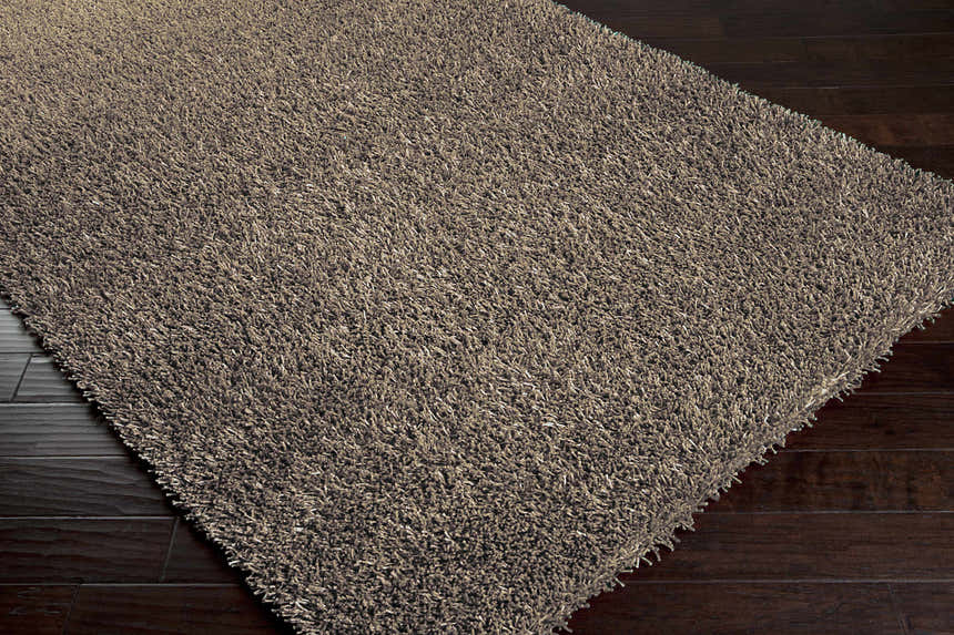 Close-up of the charcoal Morris Area Rug showing its soft, hand-woven texture on dark wood floors. Contemporary style. Corner