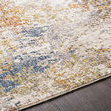 Close-up of Macayug Area Carpet showing cream, blue, gray, mustard, olive, and rust colors and soft, textured weave. Texture