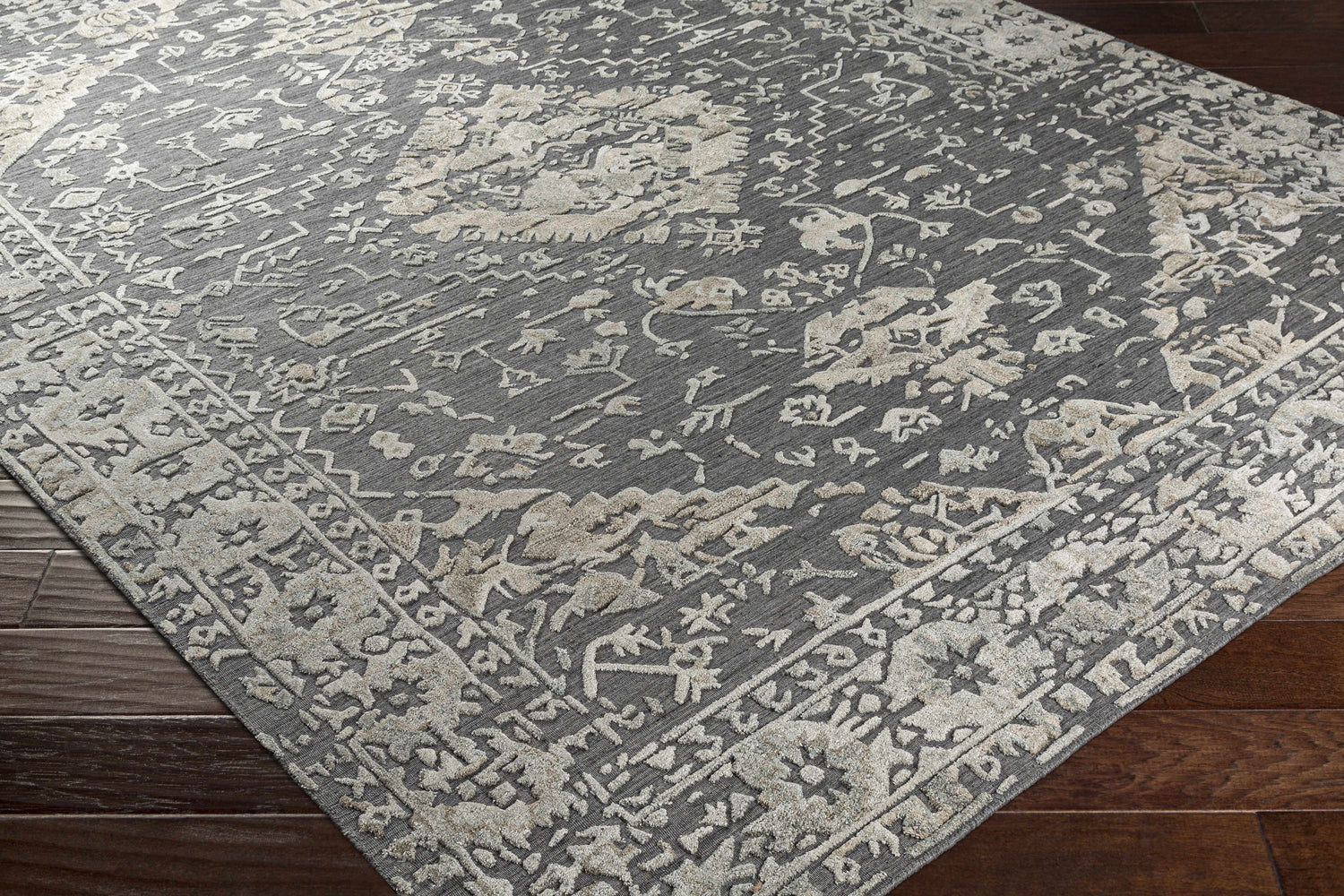 Close-up of the Macgregor Area Rug showing its charcoal base and light gray, hand-loomed, bohemian-inspired pattern and texture. Corner