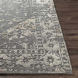 Close-up of the Macgregor Area Rug showing its charcoal base and light gray, hand-loomed, bohemian-inspired pattern. Front