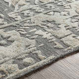 Close-up of the Macgregor Area Rug. Charcoal gray rug with a light gray, hand-loomed, bohemian-style pattern. Viscose texture. Texture