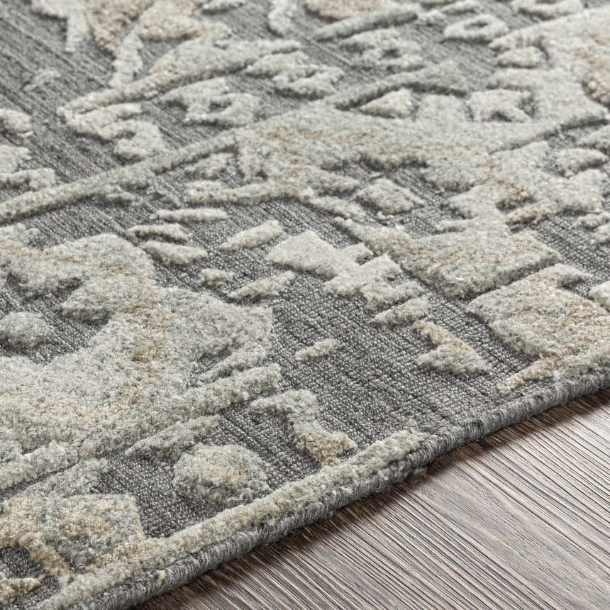 Close-up of the Macgregor Area Rug. Charcoal gray rug with a light gray, hand-loomed, bohemian-style pattern. Viscose texture. Texture