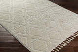 Close-up of bone Maduao Area Rug showing geometric pattern and soft texture on dark wood floor. Clearance item. Corner