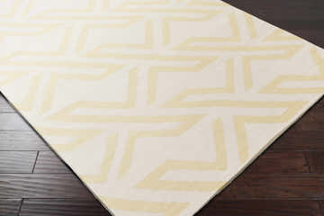 Close-up of the hand woven Malibu Area Rug. Contemporary style with a geometric pattern in ivory and pale yellow. Corner