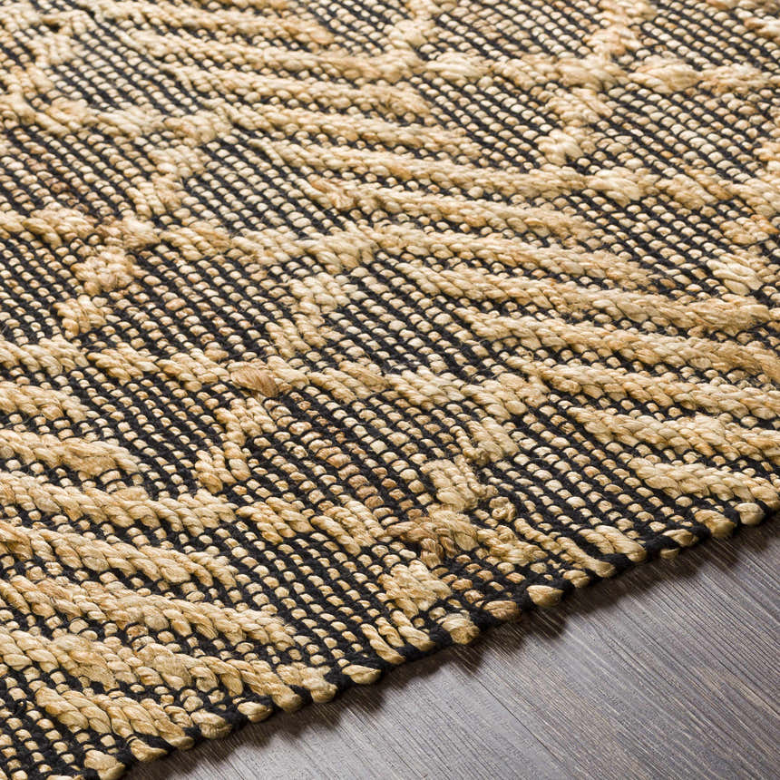 Close-up of the hand woven Malidong Jute Carpet. Black and tan geometric pattern with a textured, bohemian style. Texture