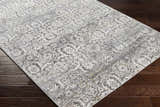 Close-up of the Mandurah Area Rug showing its charcoal, cream, and gray traditional floral pattern and machine-woven texture. Corner