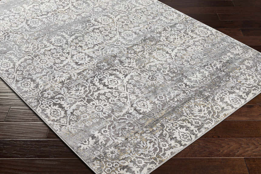 Close-up of the Mandurah Area Rug showing its charcoal, cream, and gray traditional floral pattern and machine-woven texture. Corner