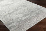 Close-up of the Mandurah Area Rug showing its charcoal, cream, and gray traditional floral pattern and machine-woven texture. Corner