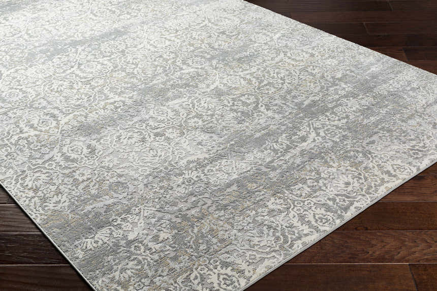 Close-up of the Mandurah Area Rug showing its charcoal, cream, and gray traditional floral pattern and machine-woven texture. Corner