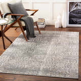 Living room scene with a charcoal and cream Mandurah Area Rug, white chair, and dark wood floors. Roomscene-Rectangle
