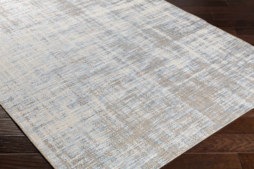 Close-up of the Manzanita Area Rug. Contemporary design in blue, cream, and taupe on dark wood floors. Corner