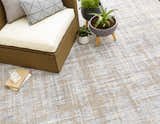 Outdoor patio scene with a blue and taupe Manzanita Area Rug, wicker chair, and potted plants. Styleshot