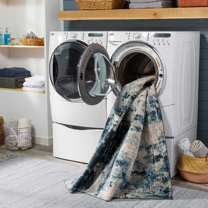Laundry room scene with the blue Masiga Washable Area Rug coming out of a white washing machine. Washing-Machine