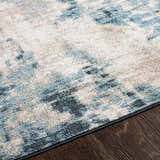 Close-up of the Masiga Washable Area Rug showing its contemporary blue, gray, and beige abstract pattern and soft texture. Texture
