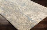 Close-up of Matewan Thick Luxe Rug. Ivory rug with blue and gold abstract pattern and plush texture. Corner