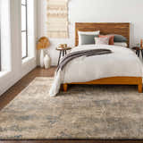 Bedroom scene with a blue and ivory Matewan Thick Luxe Rug, wood bed frame, and neutral decor. Roomscene-Rectangle