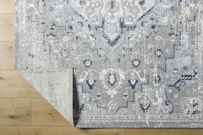 Close-up of the Mateo Area Rug, a light gray traditional rug with silver and pale slate accents. Fold