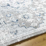 Close-up of the Mateo Area Rug, showcasing its light gray, silver, and blue traditional design and soft texture. Texture