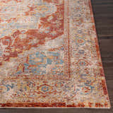 Close-up of the Powassan Area Rug showing its brick red, teal, and beige traditional design on dark wood floors. Front