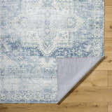Close-up of the Mauro Navy Medallion Washable Area Rug showing the traditional pattern and colors on wood floor. Fold