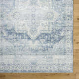 Close-up of the Mauro Navy Medallion Washable Area Rug, showing its traditional blue and gray pattern on a wood floor. Corner
