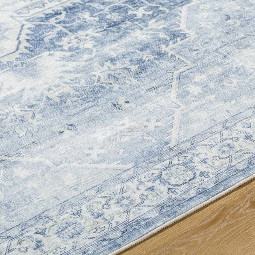 Close-up of the Mauro Navy Medallion Washable Area Rug showing its traditional light blue and gray medallion pattern. Texture