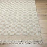 Close-up of the hand-woven Meira Tan Area Rug showing the ivory and tan checkerboard pattern and fringe detail. Front