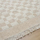 Close-up of the hand-woven Meira Tan Area Rug showing its ivory and tan geometric pattern and fringe detail. Texture