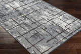 Close-up of Mace Area Rug: charcoal, cream, and slate geometric pattern on a chenille-polyester rug with a mid-century modern design. Corner